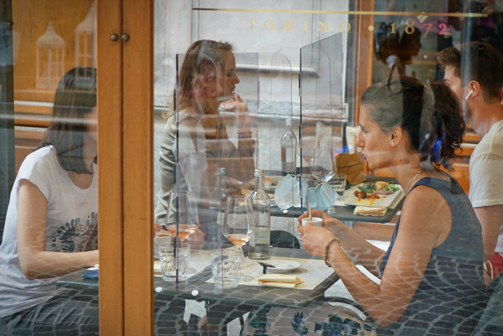 Women,Sitting,In,Restaurant,Eating,Food,With,Table,Shield,To